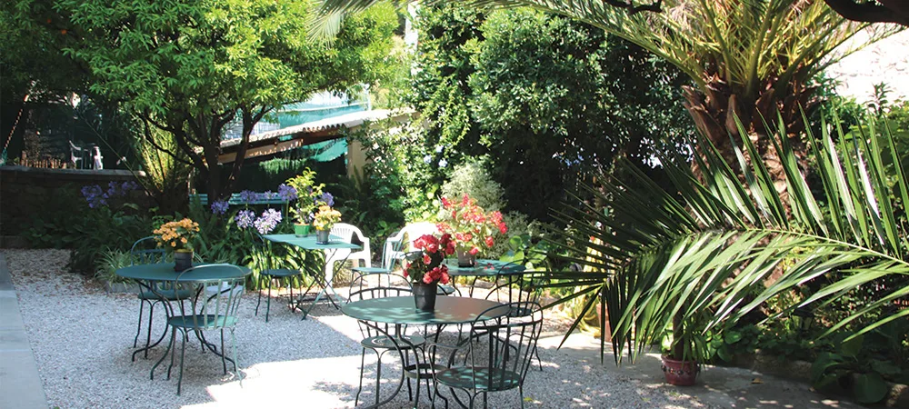 Le jardin de l'hôtel : tables en fer forgé sous les palmiers